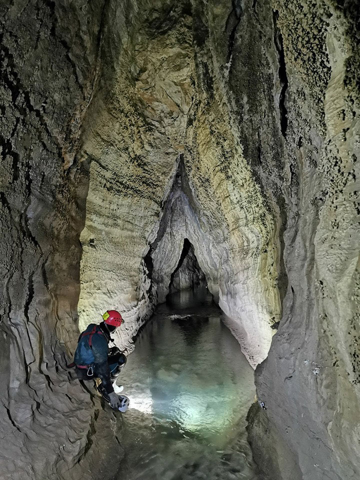 Caver looking down in water-filled cave