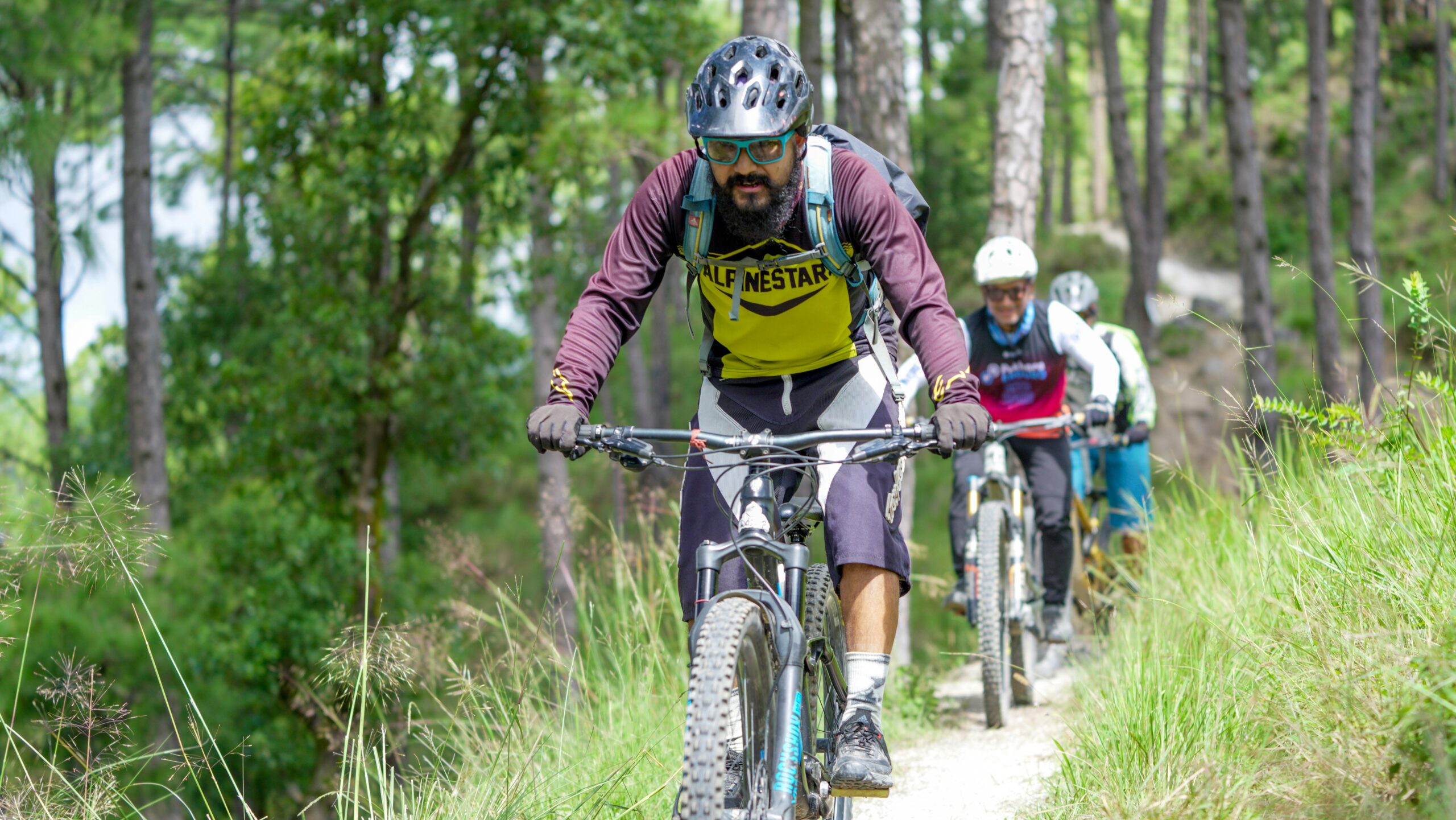 Small group of adults mountain biking a forest path