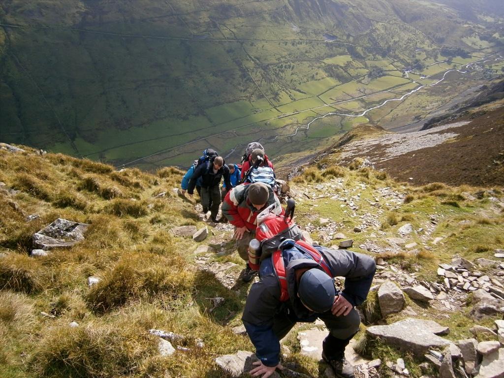 Walking group ascending steep rocky hill with views far below