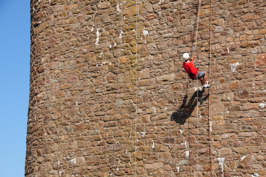Photograph of abseiler at height on brick wall