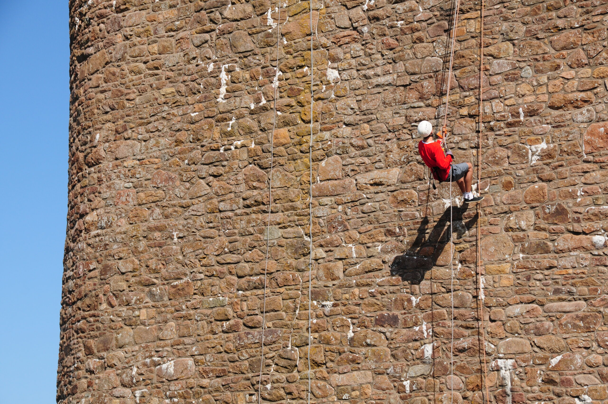 Photograph of abseiler at height on brick wall